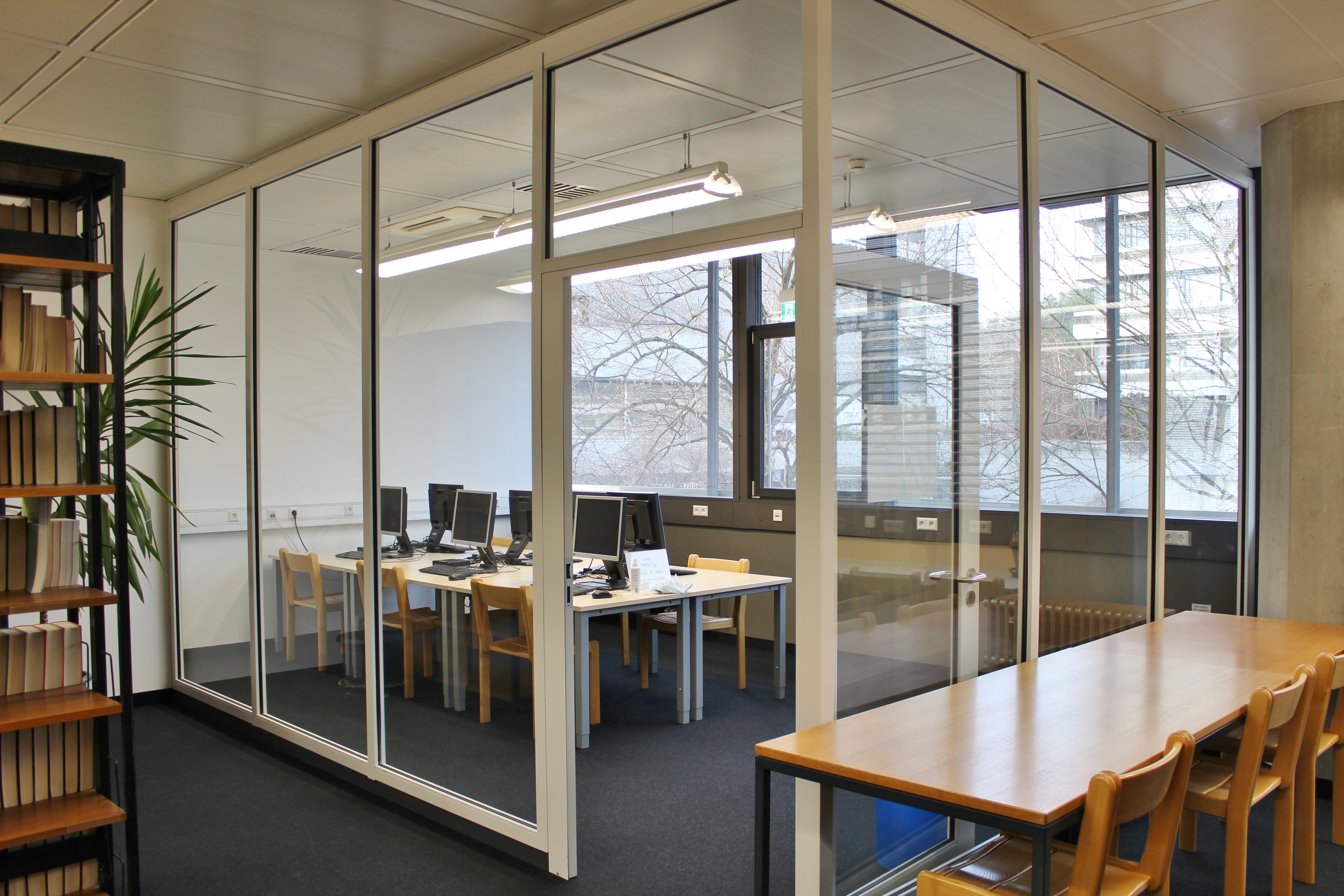 Sechs PCs stehen in einem gläsernen Raum innerhalb der Fachbibliothek. 