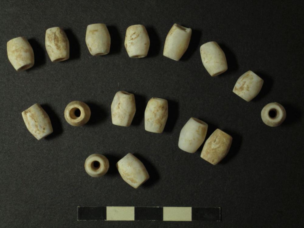 Kalksteinperlen einer Kette, die im Halsbereich der Toten gefunden wurde.