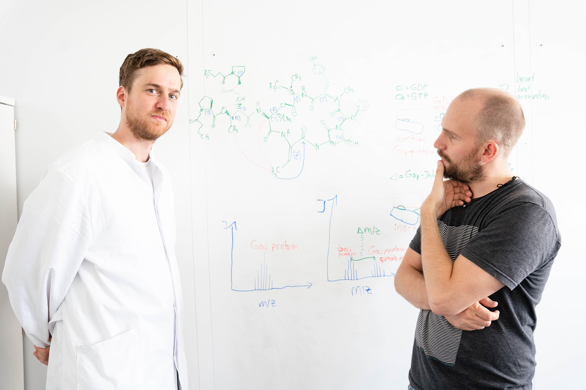 Raphael Reher (links) und Daniel Petras (rechts) diskutieren ihre Ergebnisse am Whiteboard.