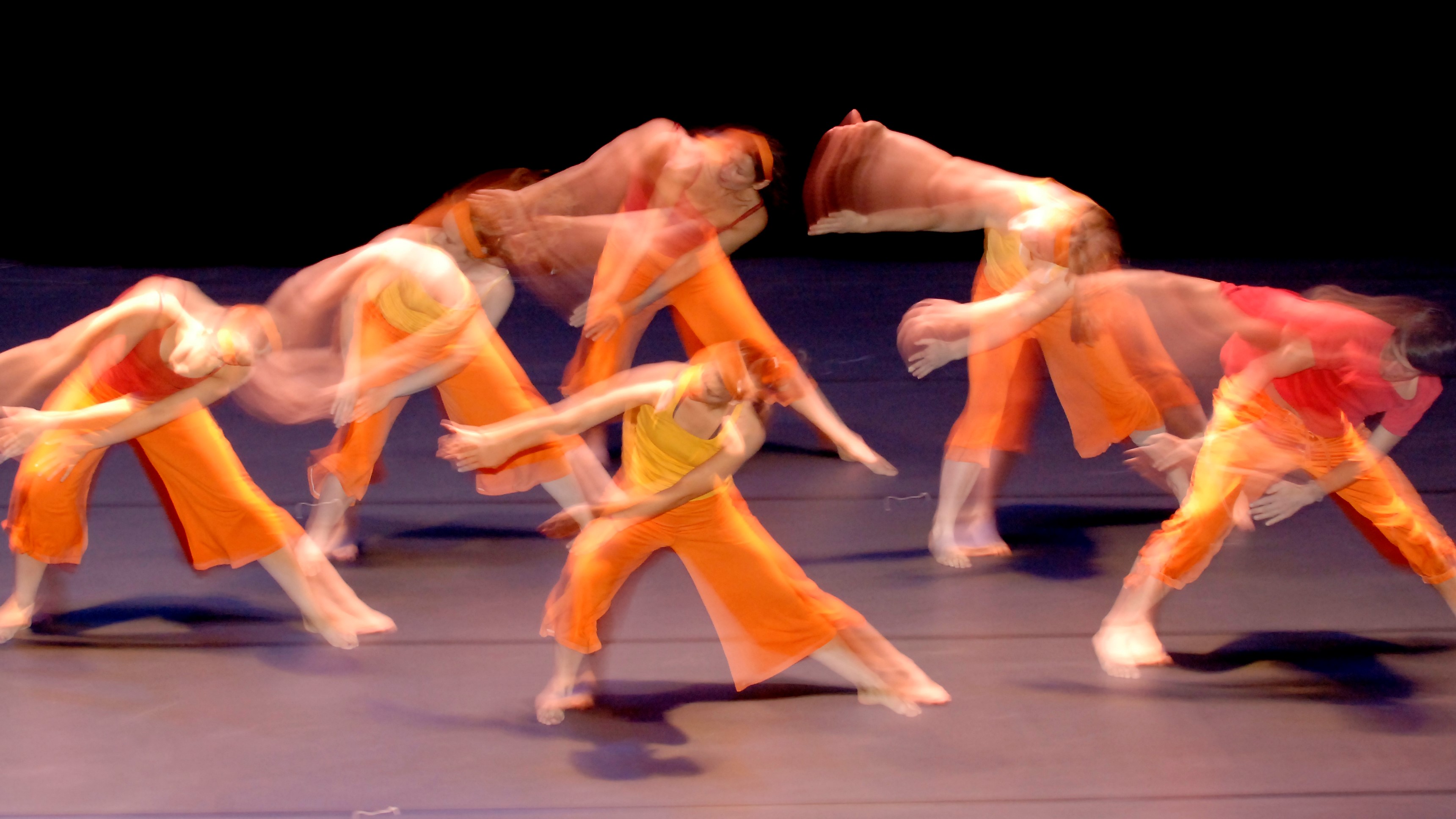 Tänzer auf einer Bühne in schwingender orangenen Kleidung