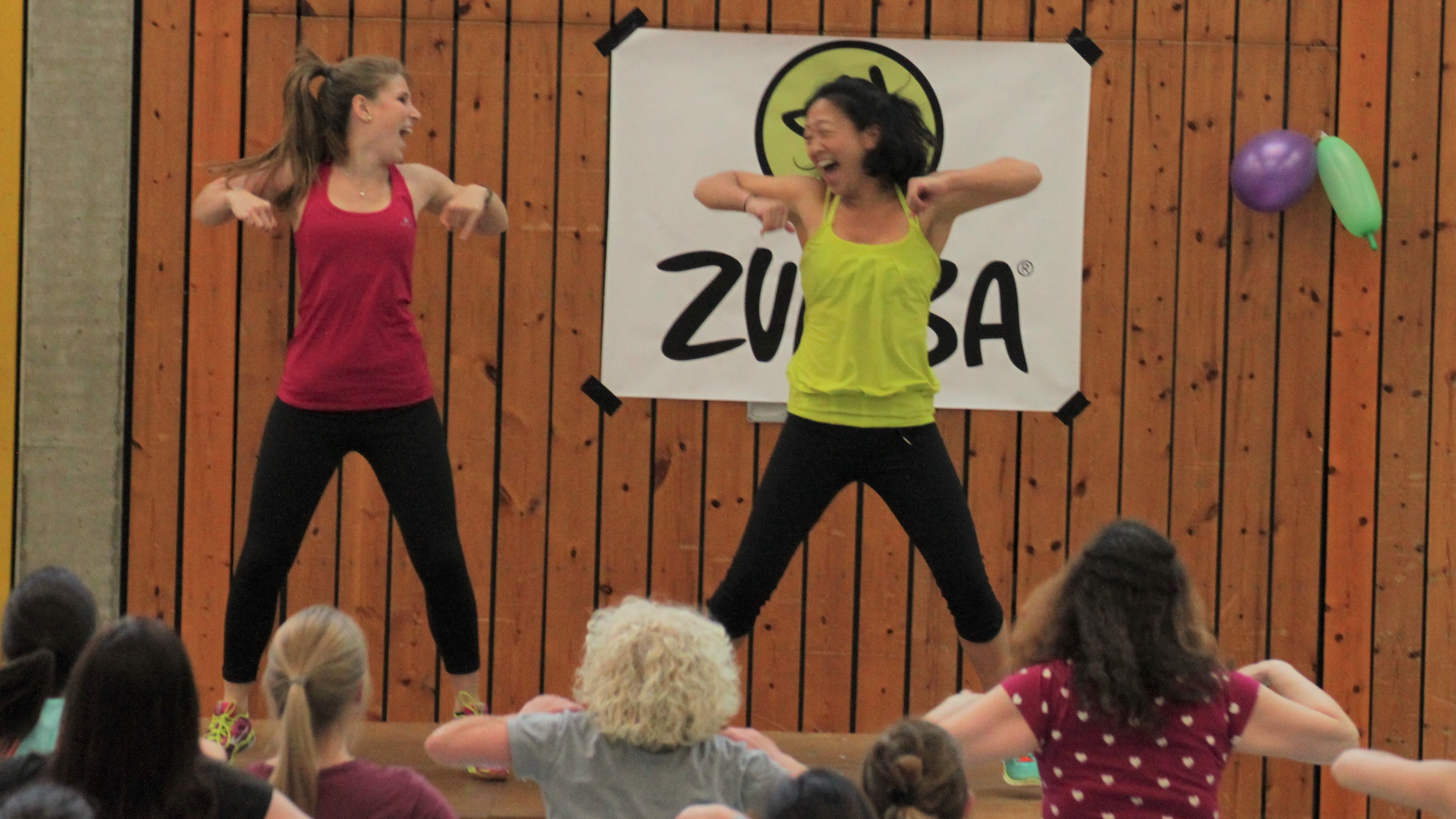Über eine Publikumsmenge auf zwei tanzende Zumba-Übungsleiterinnen schauend