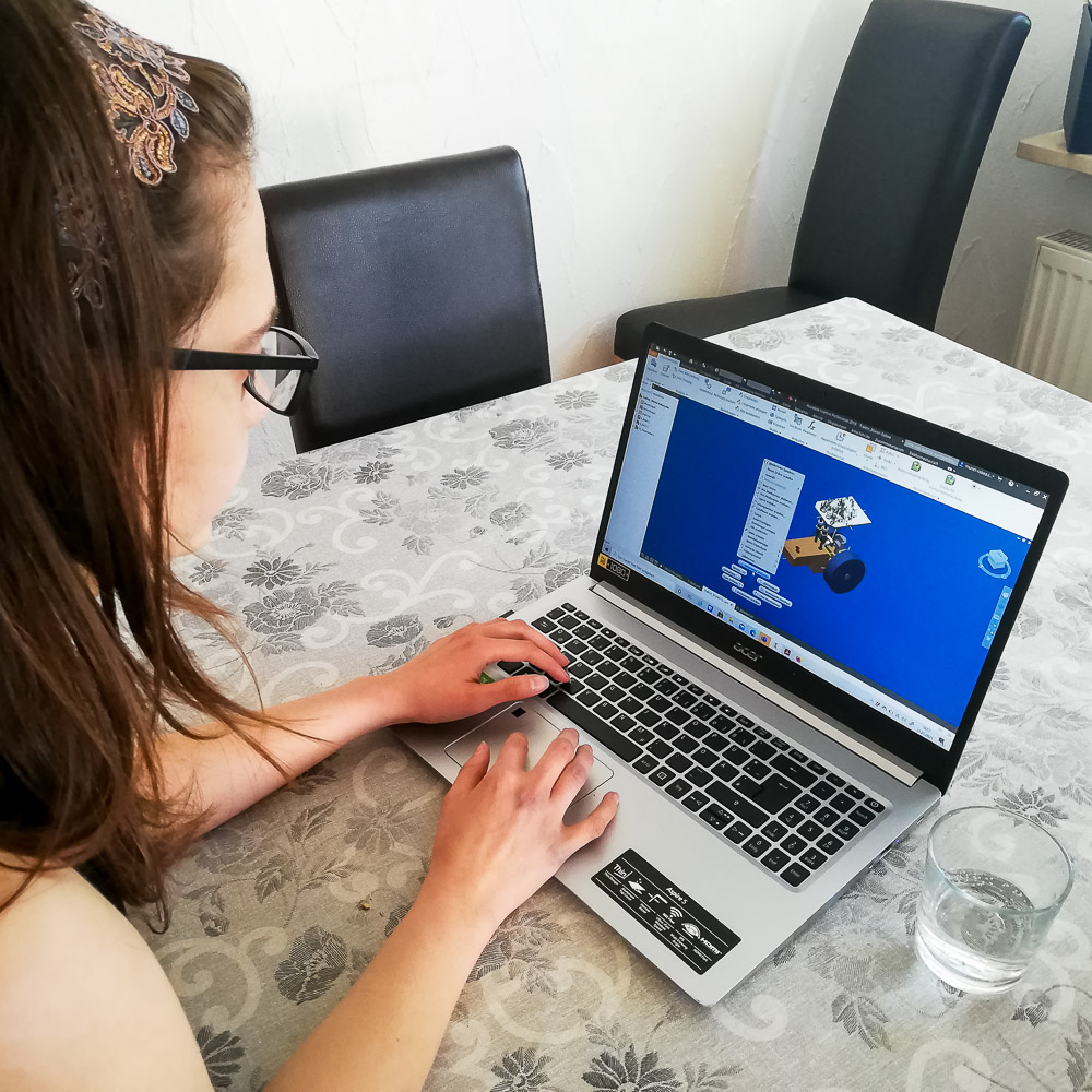 Eine Studentin konstruiert am Laptop mit einem professionellen CAD-Programm einen Spielzeug-Traktor.