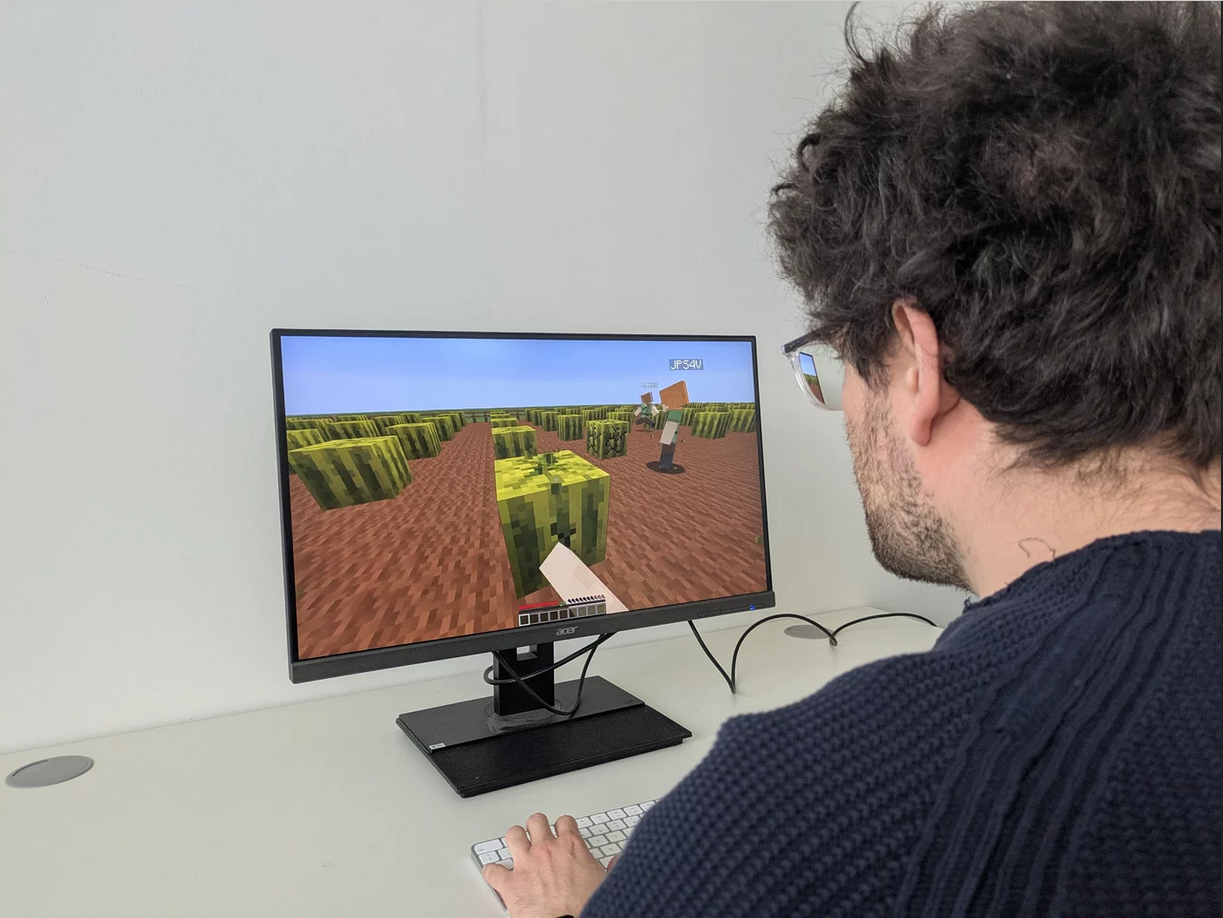 A person is sitting at a desk and playing a video game.