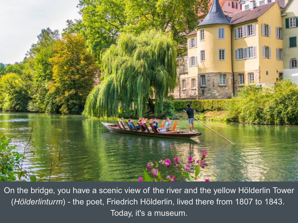 The yellow Tübingen Hölderlin Tower at the Neckar river with a willow tree just in front and a punting boat in the river