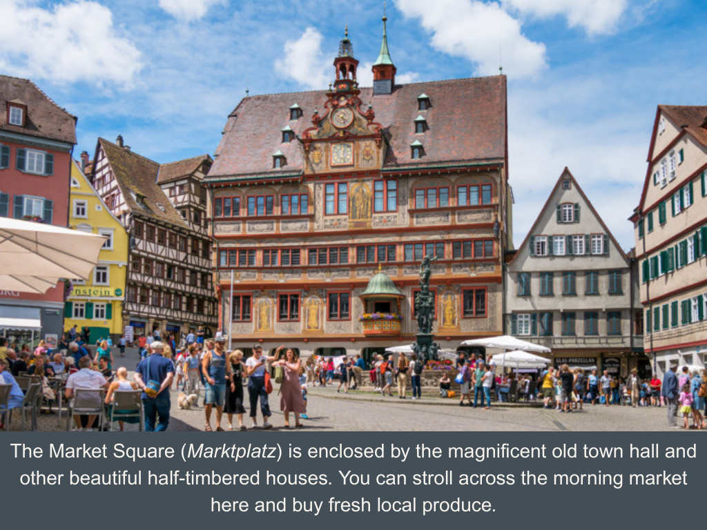 Lively town square in the middle of German medieval half-timbered houses, with the adorned town hall in the back