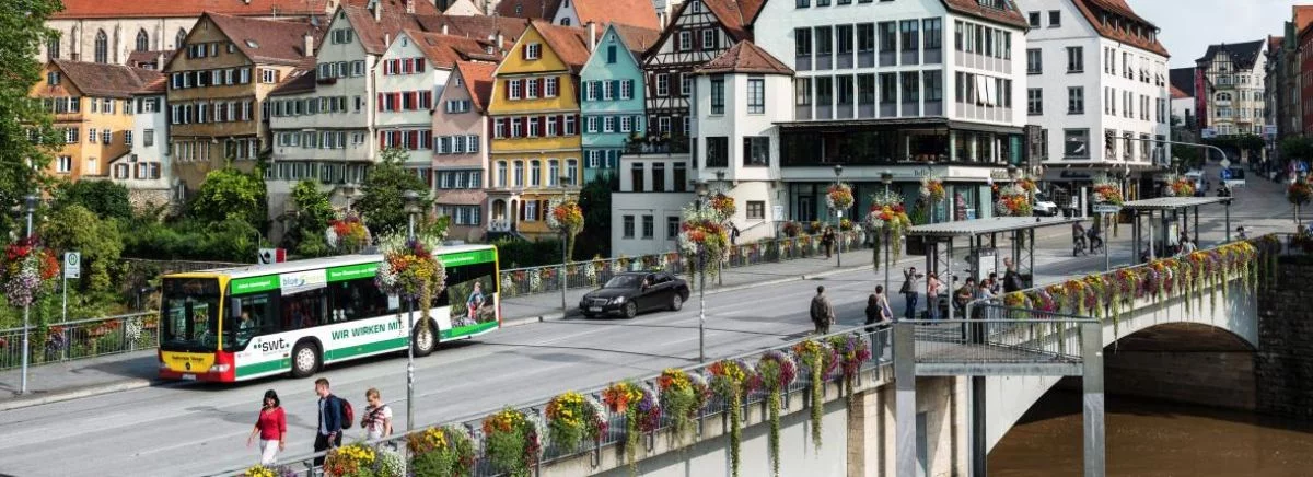 Aerial side picture of the Tübingen Neckarbridge with a Tübingen bus passing. The colorful Neckarfront is in the background.