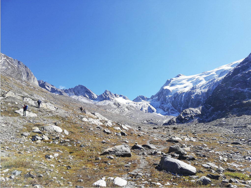 [Translate to Englisch:] Auf dem Bild ist ein beinahe vollständig zurückgezogener Gletscher zwischen Berggipfeln in den Alpen vor blauem Himmel zu sehen.