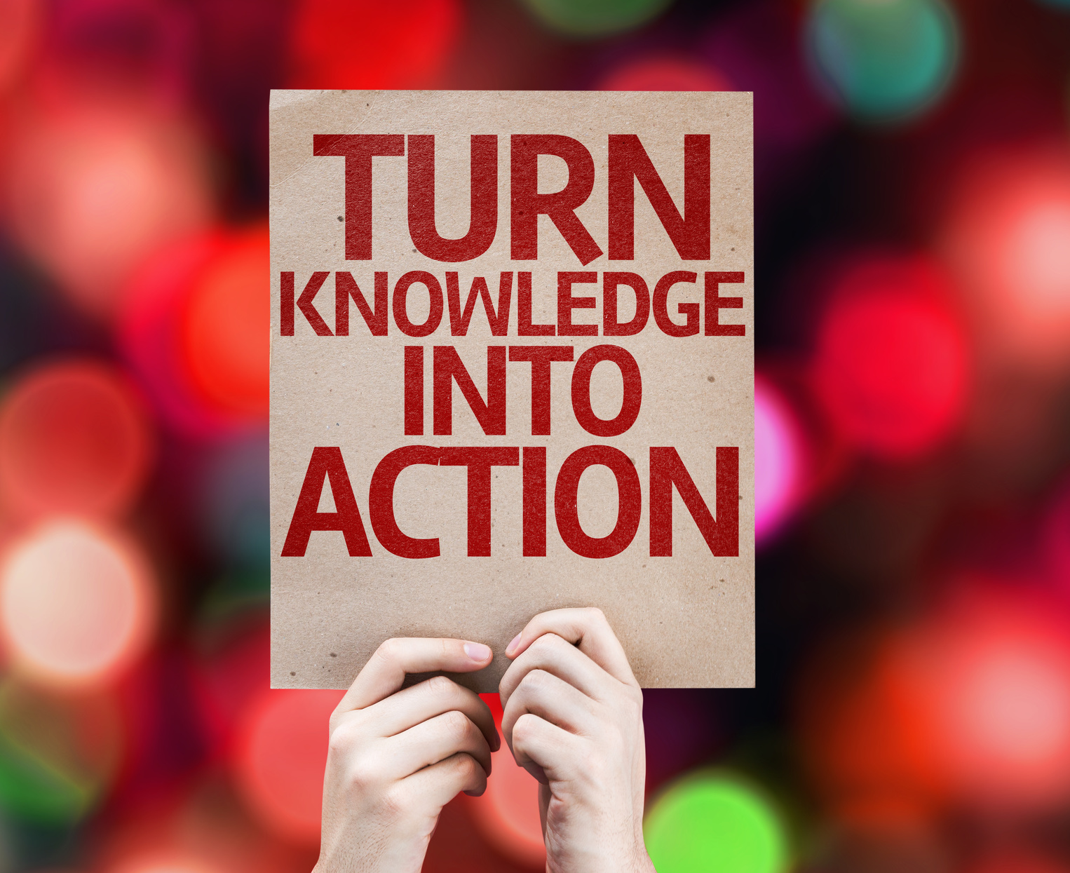 Zwei Hände halten einen Karton mit der Aufschrift "Turn Knowledge into Action".