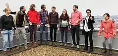 The research group of Vision and Cognition stands outside on a bannister in front of mountains