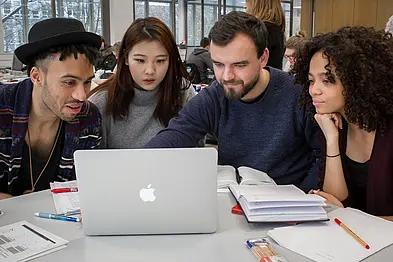 Four students looking at a laptop screen