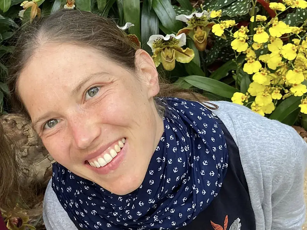 Headshot of Julia Brugger smiling into the camera in front of various plants.