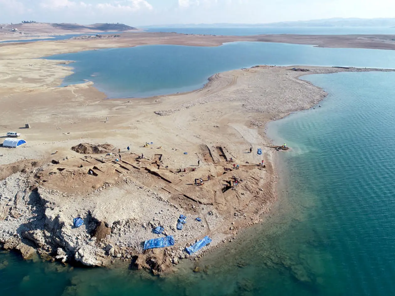 Zu sehen ist die archäologische Stätte von Kemune im ausgetrockneten Bereich des Mosul-Stausees. Ringsherum ist Wasser.