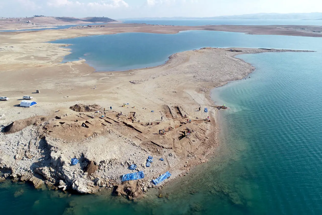 Zu sehen ist die archäologische Stätte von Kemune im ausgetrockneten Bereich des Mosul-Stausees. Ringsherum ist Wasser.