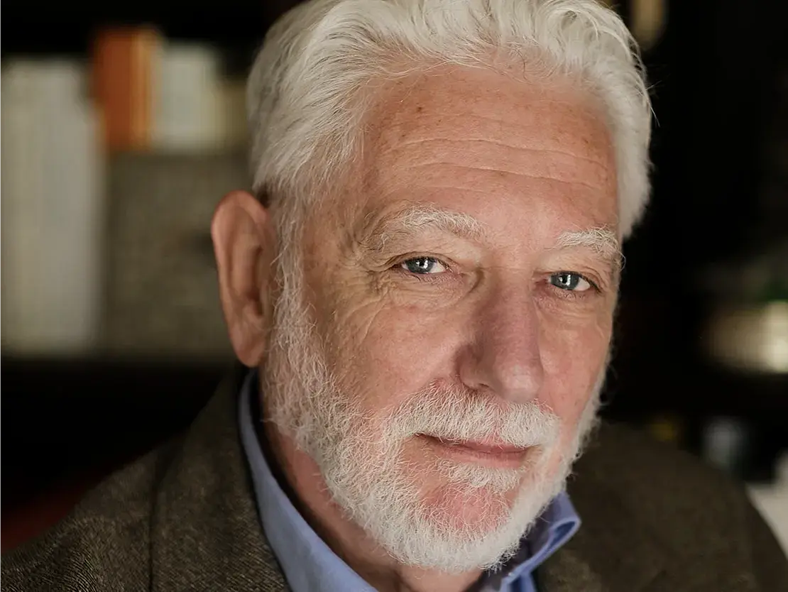 man with white hair and beard looking into the camera