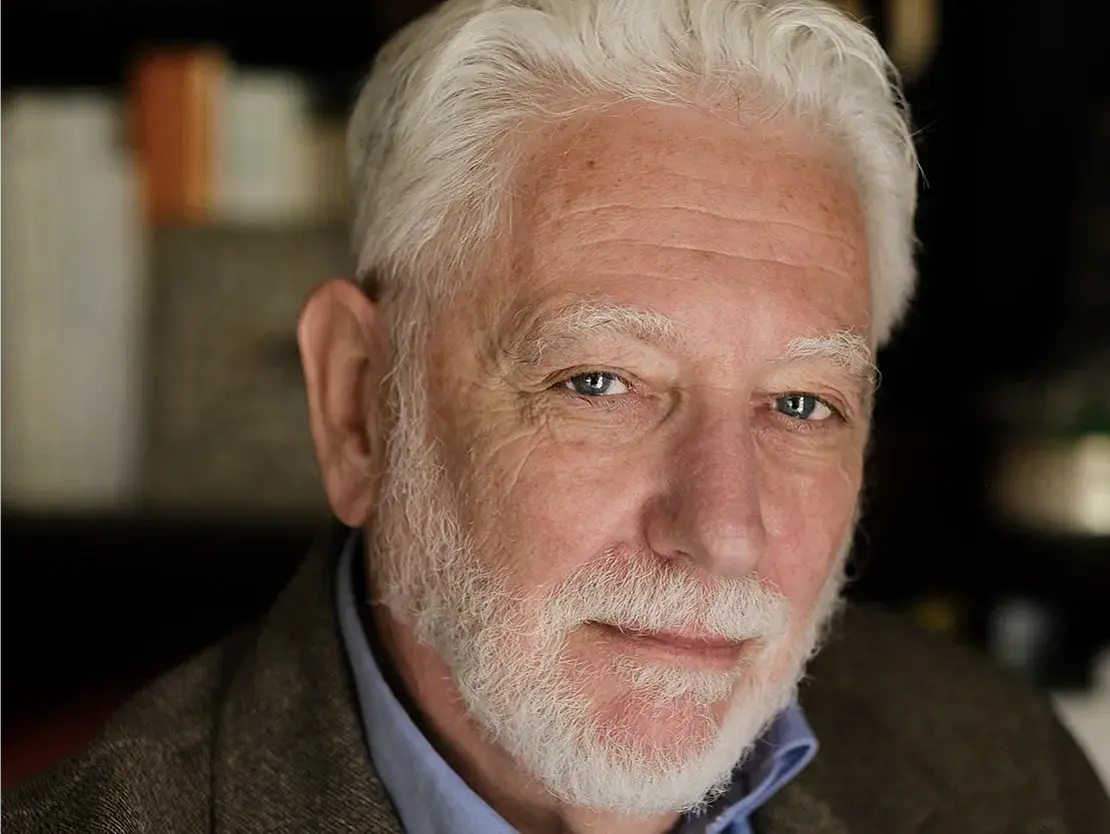 man with white hair and beard looking into the camera