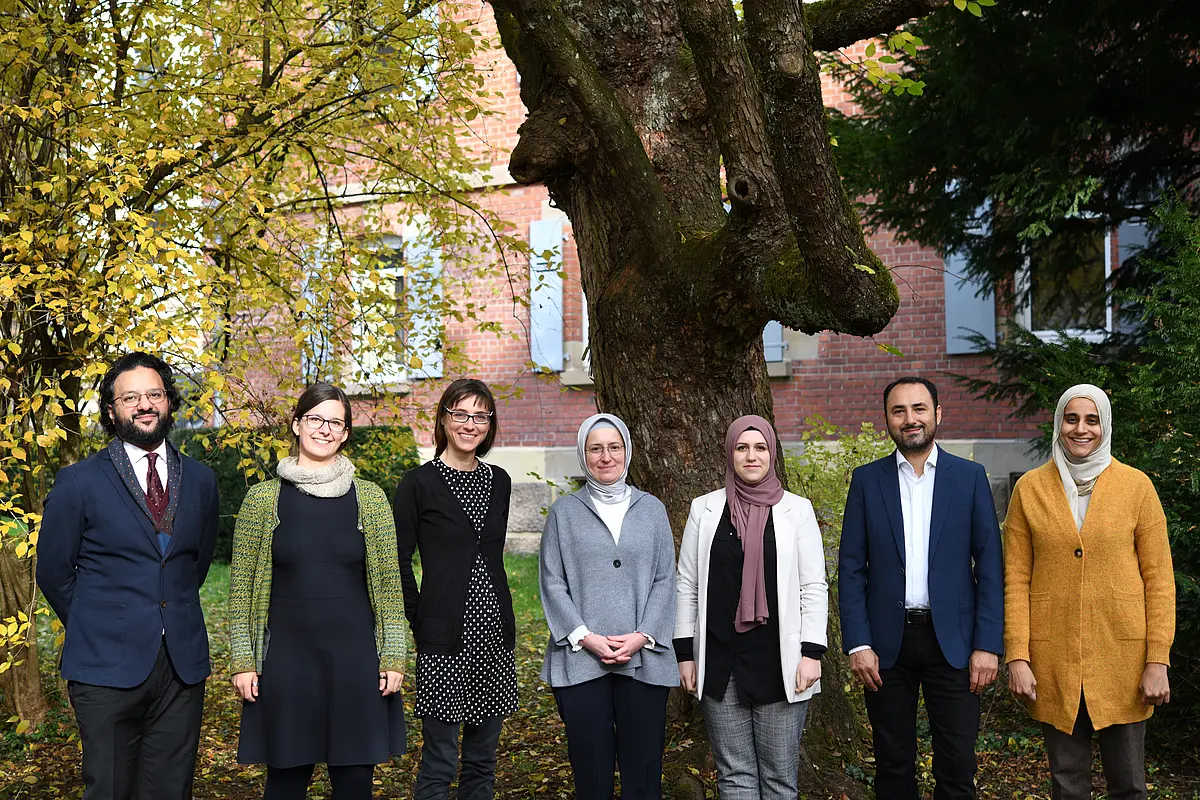 Sieben Personen vor einem Baum
