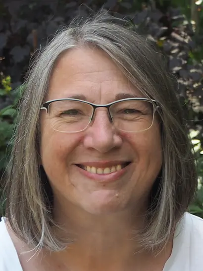 Ein Porträtfoto von Frau Kirsten Schirrmeister mit braunem Haar und einer Brille, lächeld