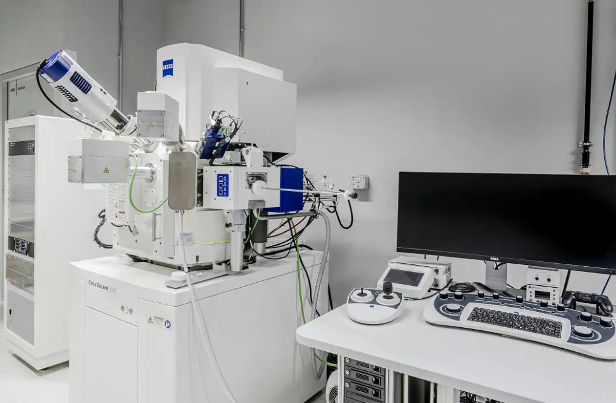 Photo of the Cryo-FIB-SEM electron microscope. On the right is a desk with a large screen and keyboard.