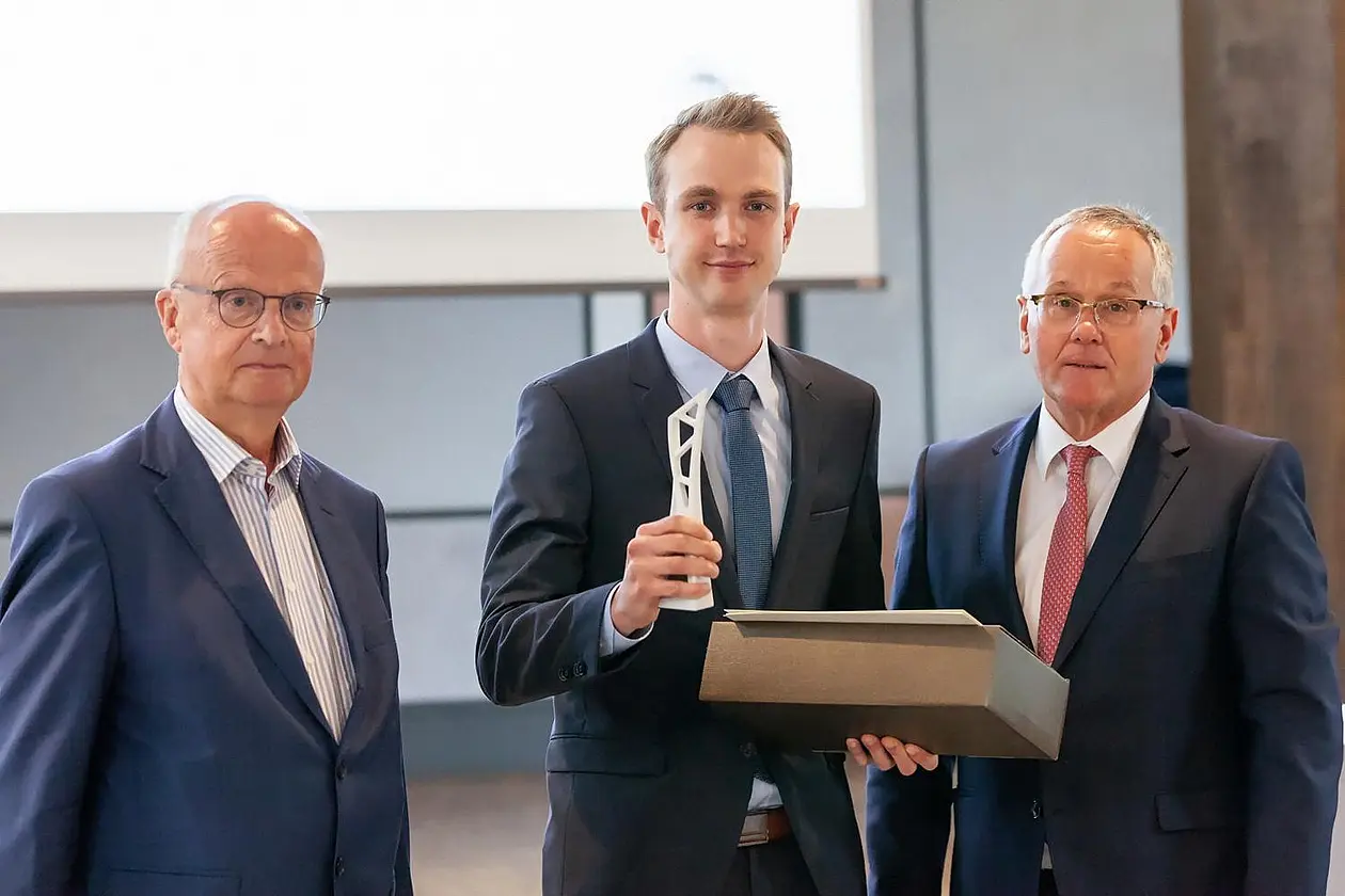 Tobias Merkle steht zwischen Peter Frankenberg und Stefan Hofmann und hält eine kleine Skulptur und ein Päckchen