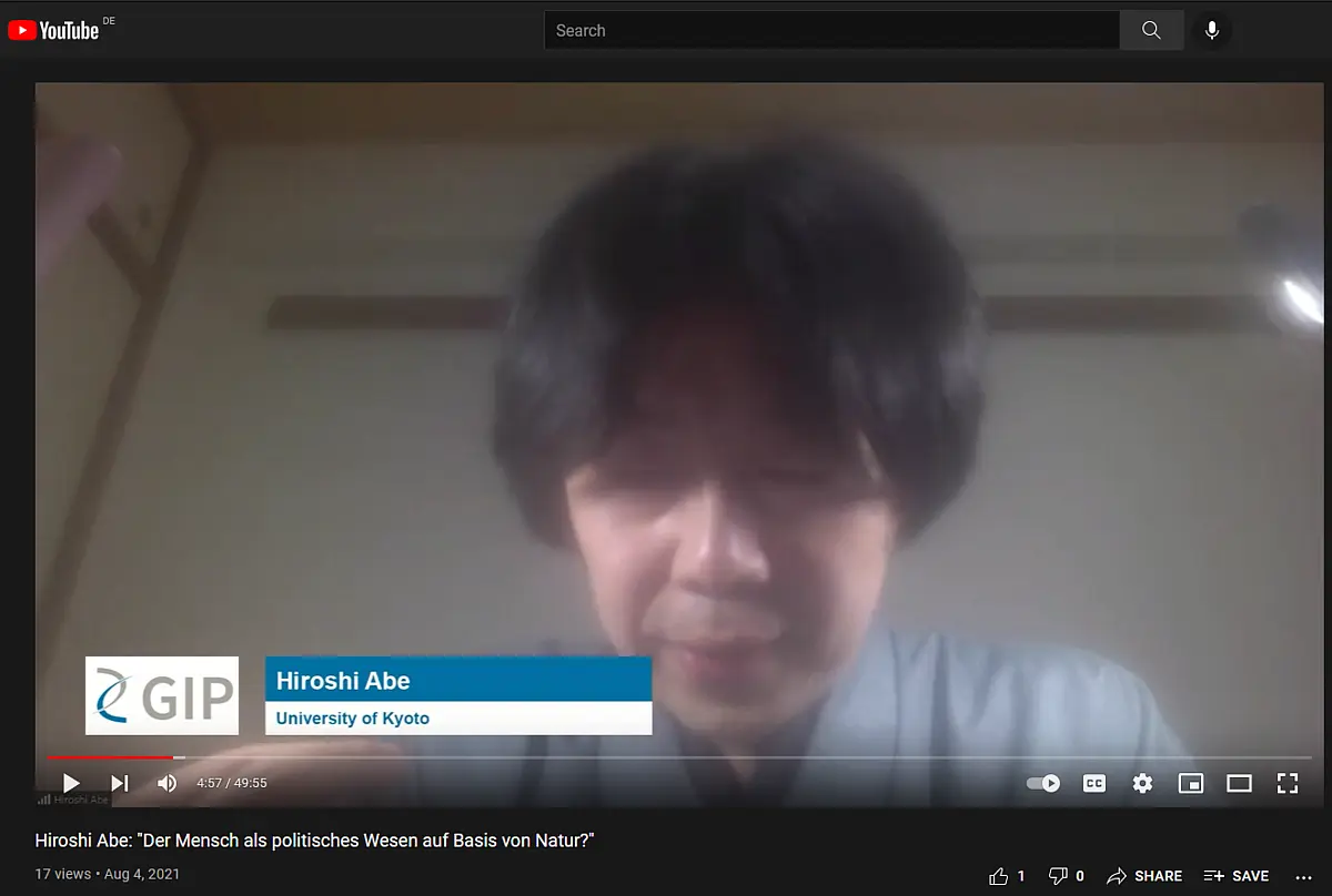 A middle-aged man with dark hair speaking into a webcam