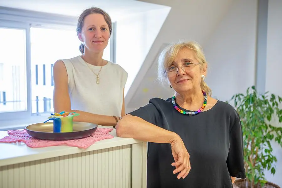 Annette Mauch (links im Bild) und Karla Polen-Beer stehend im Büro. Frau Polen-Beer hat den Arm auf einen Schrank gelehnt.