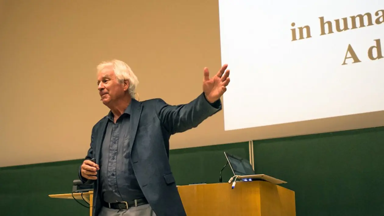 Prof. Peter Gärdenfors stands in front of the lectern during his lecture and points to his presentation
