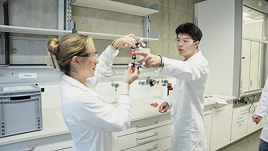 Eine Mitarbeiterin der Chemiedidaktik im Austausch mit Schülern im TüChemLab. 