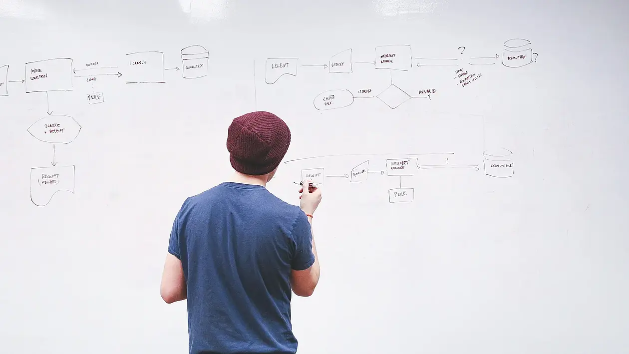 Auf diesem Symbolbild ist ein Mensch zu sehen, der auf einem Whiteboard Notizen macht.