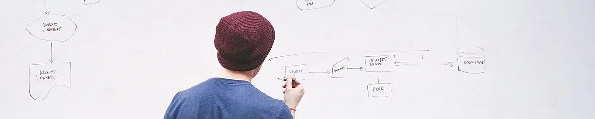 Auf diesem Symbolbild ist ein Mensch zu sehen, der auf einem Whiteboard Notizen macht.