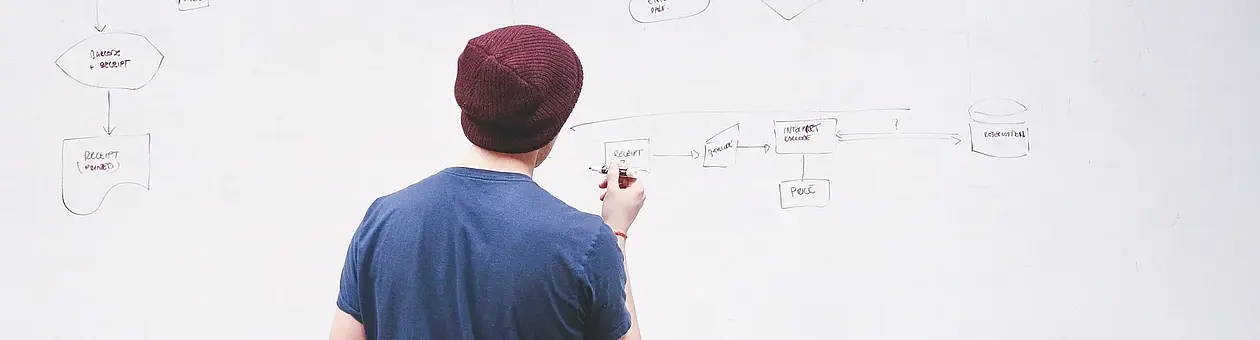 Auf diesem Symbolbild ist ein Mensch zu sehen, der auf einem Whiteboard Notizen macht.