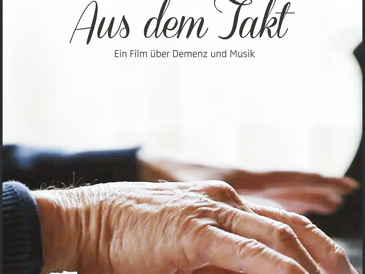 Das Bild zeigt ein DVD-Cover des Films **„Aus dem Takt“**. Es zeigt die Nahaufnahme einer älteren Hand, die auf einer Klaviertastatur spielt. Der Titel des Films „Aus dem Takt“ ist in eleganter Schrift zu lesen, mit dem Untertitel „Wenn Demenz den Rhythmus vorgibt“. Am unteren Rand stehen die Namen der Regisseur*innen (*Constanze Ramsperger, Oliver Lichtwald, Christoph Jäckle*). Außerdem sind das FSK-Symbol („ab 0 freigegeben“) und das Logo von „good!movies“ zu sehen. Der Hintergrund ist minimalistisch in Weiß gehalten, wodurch die Hände und der Titel im Fokus stehen.
