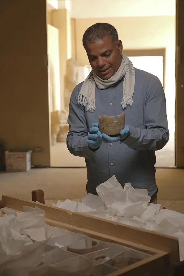 Dr. Ramadan Hussein untersucht einen Töpferkrug im Lagerraum von Sakkara.