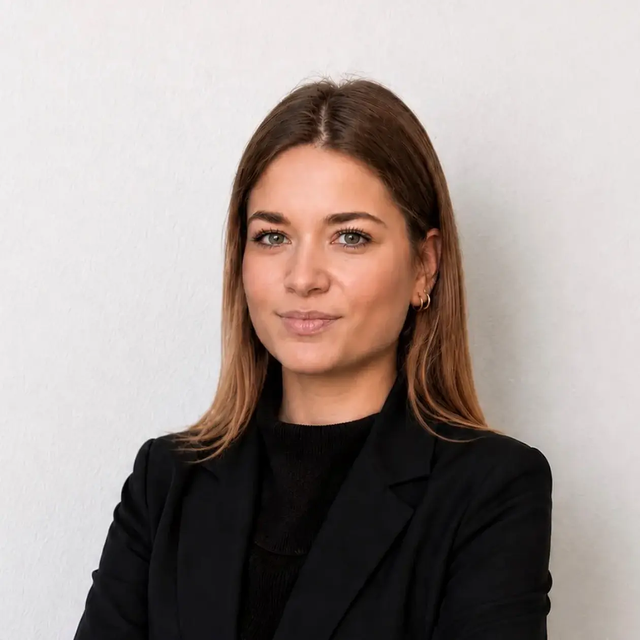 A profile photo of Katharina Christou, a white woman with long brown hair, smiling at the camera, wearing a black shirt and a black blazer. 