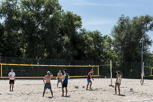 A few people playing beach volleyball in the sun