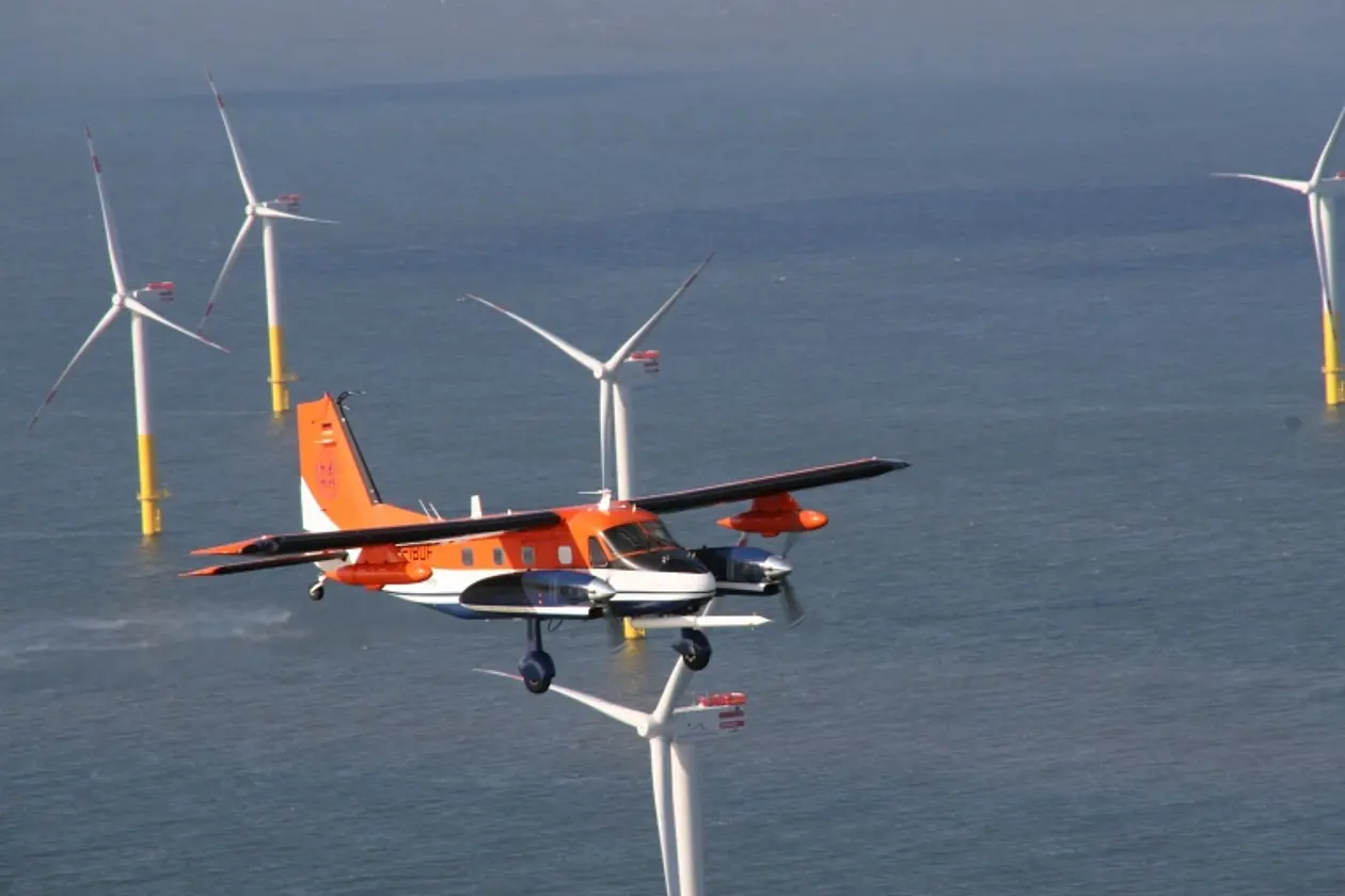 Messflugzeug DO-128 der Technischen Universität Braunschweig beim Flug über Windkraftanlagen am Meer. 