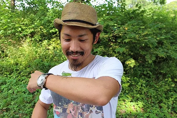Dr. Wataru Toyokawa, draußen, mit einer Heuschrecke auf dem Arm
