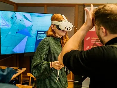 Person mit VR-Brille vor Bildschirm