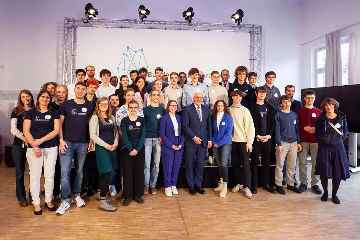 BWKI-Finalisten/innen, -Team und -Ehemalige haben sich mit Bundespräsident Steinmeier für ein Gruppenfoto aufgestellt. Der Bundespräsident steht vorne in der Mitte.