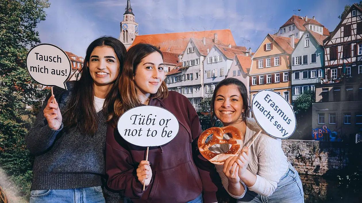 Studierende mit Schildern in der Hand mit Fotomotiv im Hintergrund. 