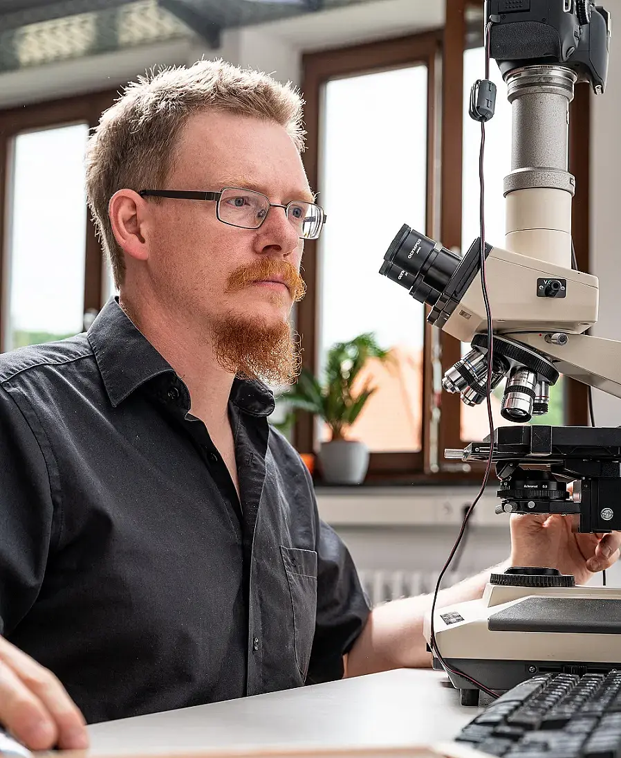 Portrait of PD Dr. Ingmar Werneburg in front of a microscope