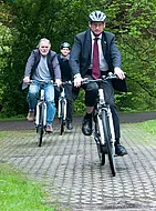 Kanzler Dr. Andreas Rothfuß (vorne), Walter Heim (Zentrum für Datenverarbeitung, links) und Jörg Schäfer (Stabsstelle Hochschulkommunikation) bei einer Testfahrt mit den neuen Pedelecs.
