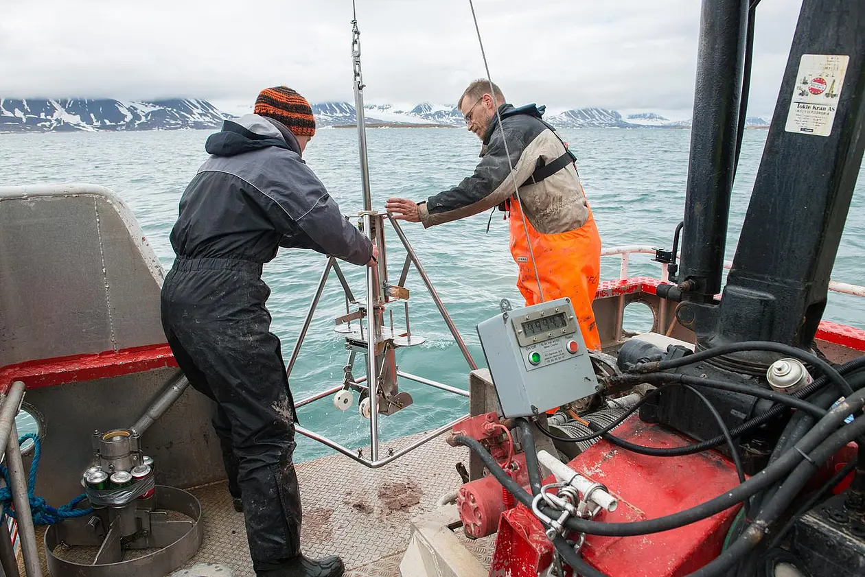 Zwei Wissenschaftler nehmen in einem Fjord in Spitzbergern Sedimentproben. 