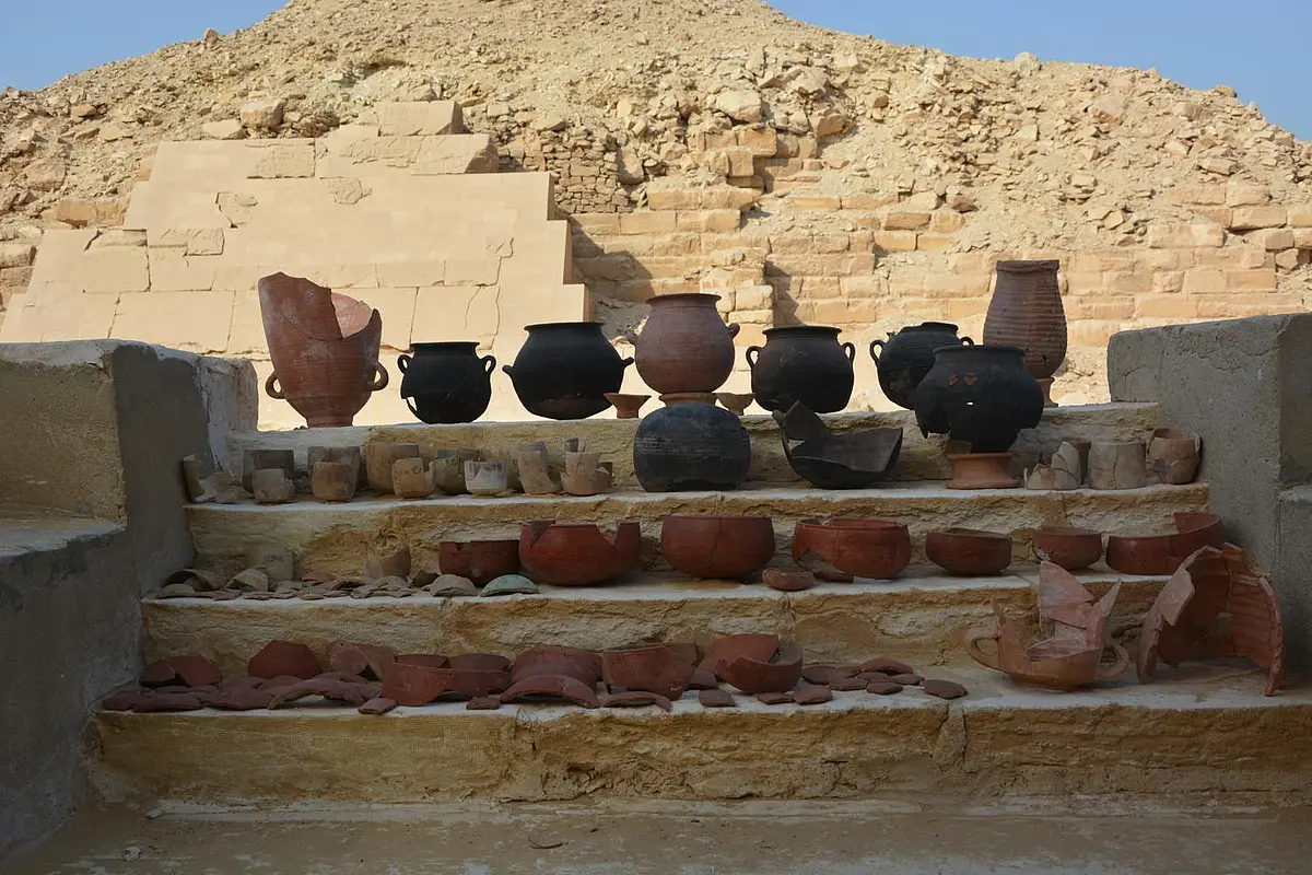 Gefäße aufgereiht auf einer Treppe, im Hintergrund Teil einer Pyramide