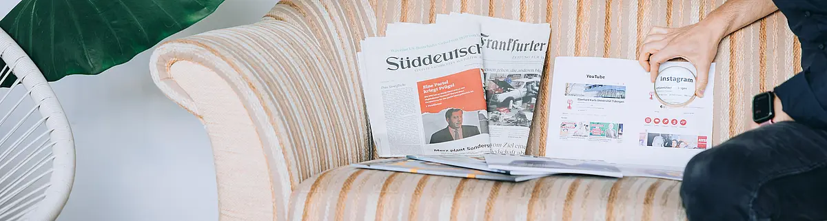 Auf einem Sofa sind Zeitungen platziert und vergrößert sieht man den Schriftzug 'Instagram'.