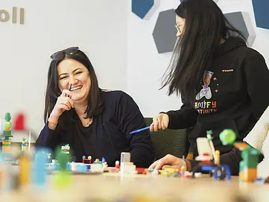 Personen im Gespräch am Tisch mit Legosteinen
