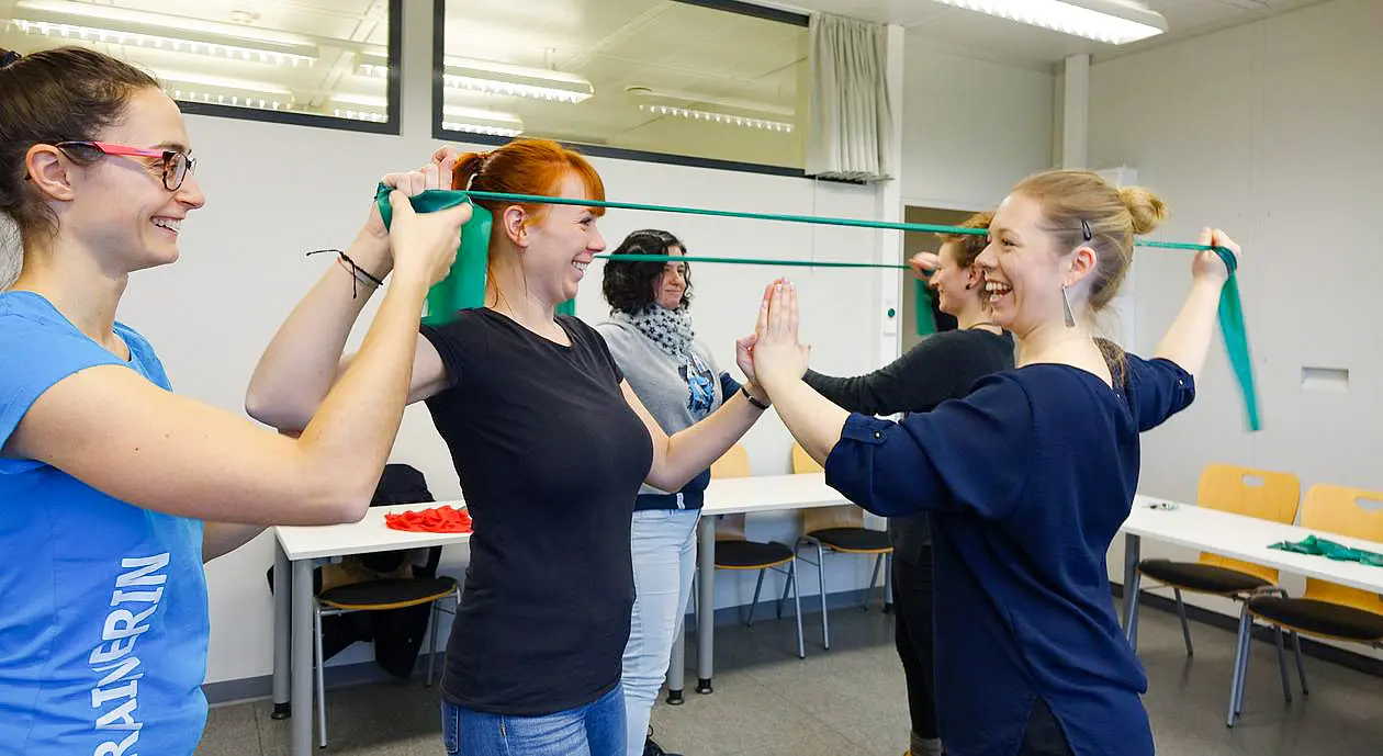 Personen bei einer kleinen Sporteinheit im Büro mit Therabändern