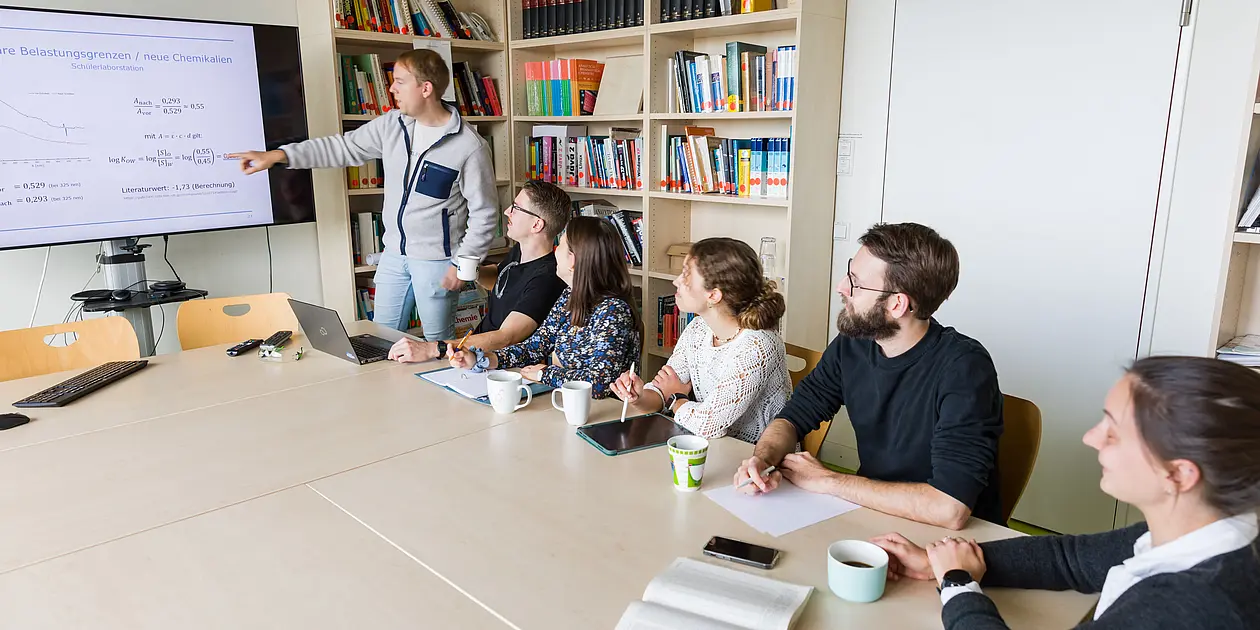 Foto einer Teambesprechung mit einer Präsentation auf einem großen Display im Besprechungsraum