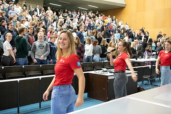 Three students instruct a lecture hall full of people to move their body.
