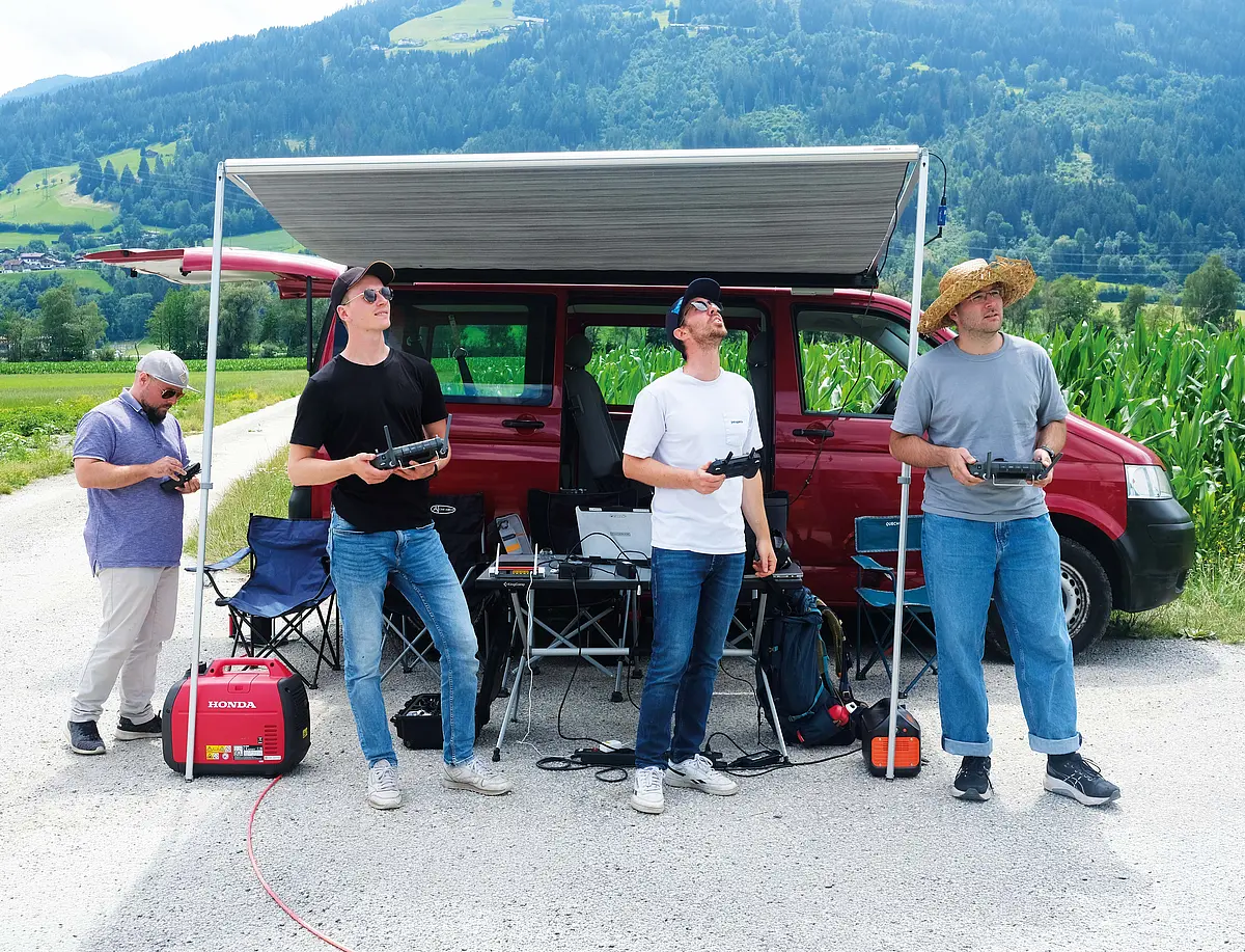 Andreas Platis (zweiter von rechts) und Mitarbeiter seines Forschungsteams stehe vir einem Auto und steuern die Drohnen mit einem Steuerungsgerät. 