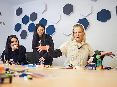 Personen im Gespräch am Tisch mit Legosteinen